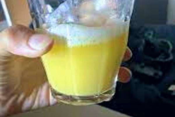 Main tenant un verre de jus de pomme de terre jaune.