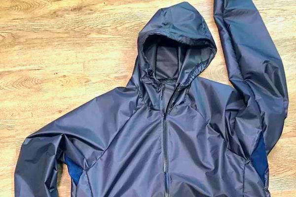 K-Way bleu marine étendu sur parquet : laver sans altérer le tissu.