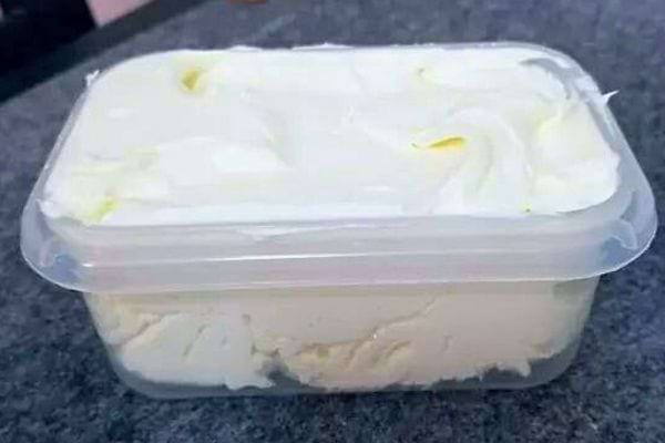 Un récipient en plastique transparent rempli de mascarpone frais et lisse.