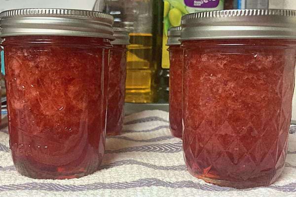 Confiture rougeâtre dans des pots en verre.