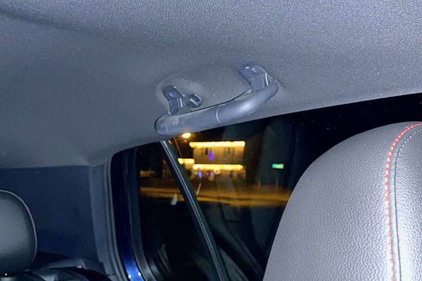Poign&eacute;e de maintien int&eacute;rieure de voiture vue &agrave; travers la vitre arri&egrave;re, de nuit.