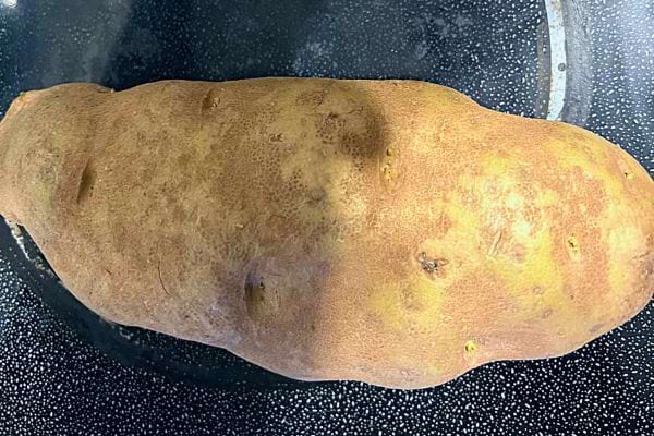 Pomme de terre crue entière sur une surface sombre.