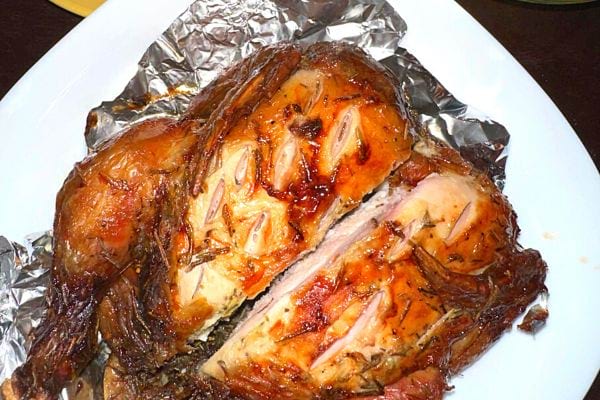 Un poulet rôti entier enveloppé dans du papier d'aluminium, conservant l'humidité.