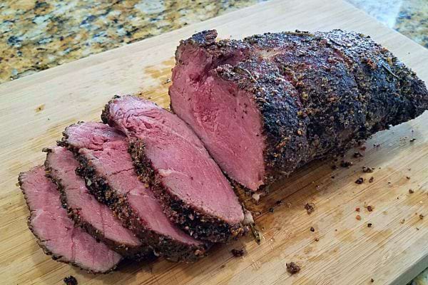 Viande rôtie tranchée sur une planche à découper.