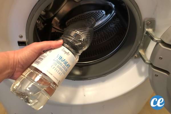 Une bouteille de vinaigre blanc qui est versé dans la machine à laver