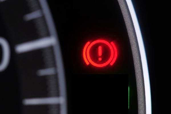 Témoin rouge d'exclamation dans un cercle, sur fond noir de tableau de bord de voiture