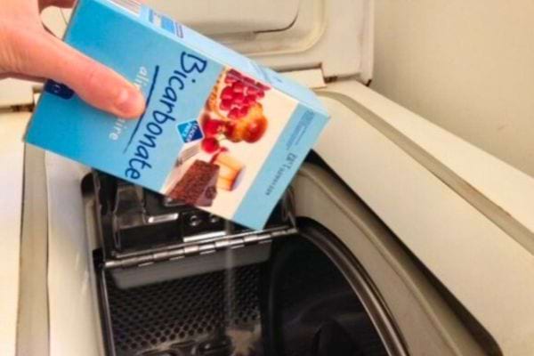 Main versant du bicarbonate de soude dans le bac à lessive.