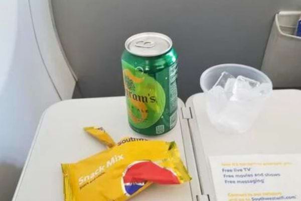 Une canette de soda et un paquet de snacks sur une tablette dans un avion.