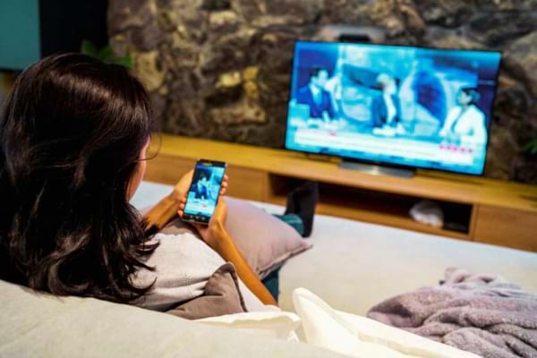 Une femme qui cast une vidéo de son téléphone vers la télévision qui n'a pas d'antenne