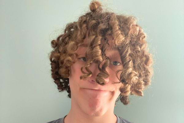 Un garçon souriant avec des cheveux bouclés.