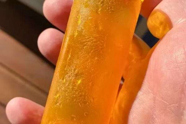 Tube de colle orange avec des marques blanches indiquant des résidus.