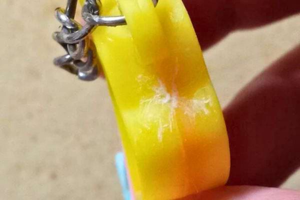 Porte-clés jaune en plastique avec des résidus blancs de colle.