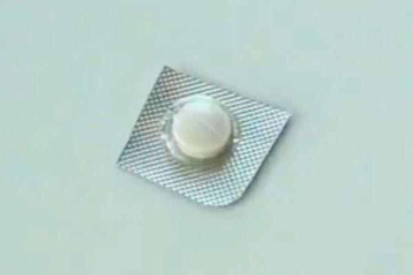 Comprimé intact dans un blister sur une surface claire.