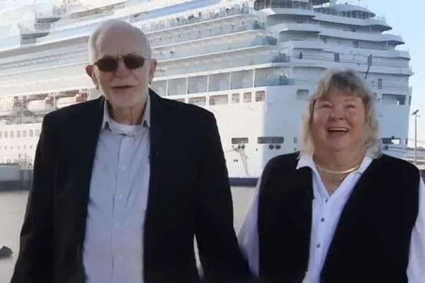 Couple &eacute;l&eacute;gamment v&ecirc;tu se tenant la main devant un grand navire de croisi&egrave;re.