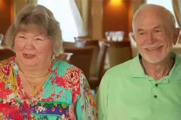 Un couple souriant sur un navire de croisi&egrave;re, l'homme porte une chemise verte.