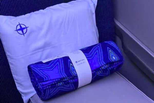 Une couverture pliée et un oreiller sur un siège d'avion.