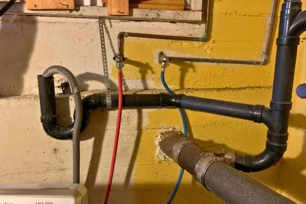 Tuyaux d'une machine à laver installée dans une cave.