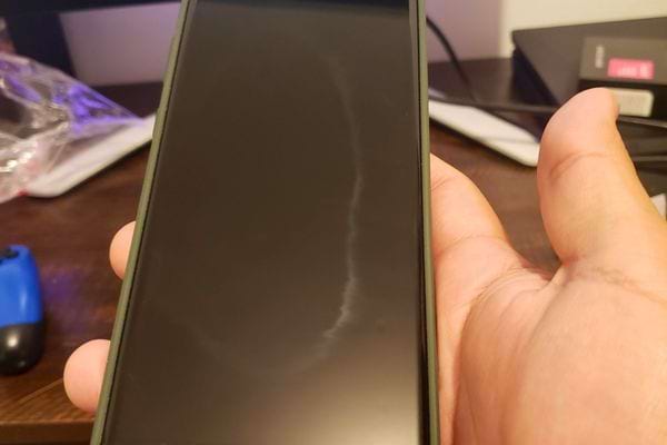 un téléphone avec un écran propre sans rayures, posé sur une table en bois