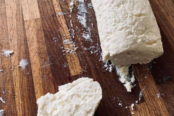 Fromage de chèvre frais émietté sur une planche en bois.