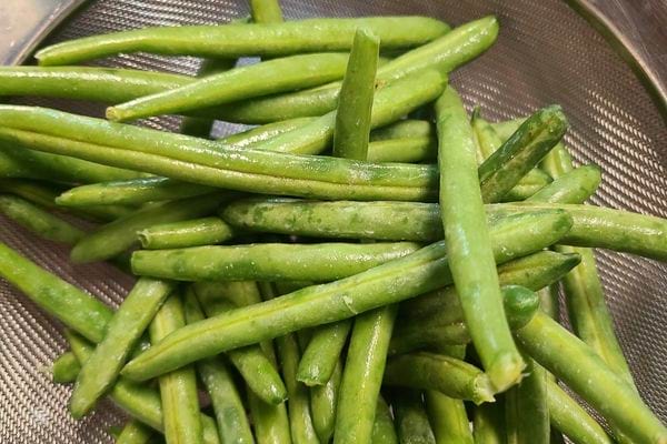 Les haricots verts s'égouttent dans une passoire grise