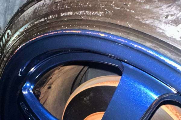 Nettoyage détaillé d'une jante de voiture bleu métallique avec une accumulation de saleté.