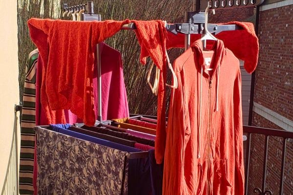 Linge rouge vibrant suspendu sur un balcon, risque d'humidité prolongée la nuit.