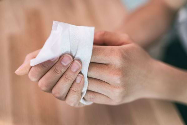 Une personne tenant des lingettes désinfectantes.
