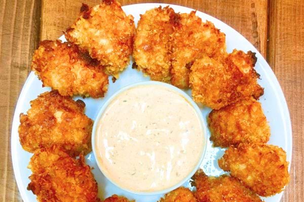 Des nuggets de poulet croustillants accompagnés d'une sauce crémeuse dans une assiette.