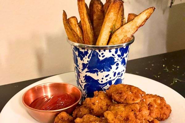 Des nuggets de poulet croustillants servis avec des frites dorées et de la sauce ketchup.