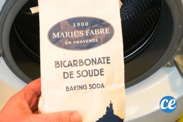 un paquet de bicarbonate de soude devant le tambour d'une machine à laver