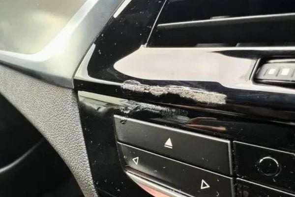 Tableau de bord en plastique noir avec des traces de colle rugueuses.