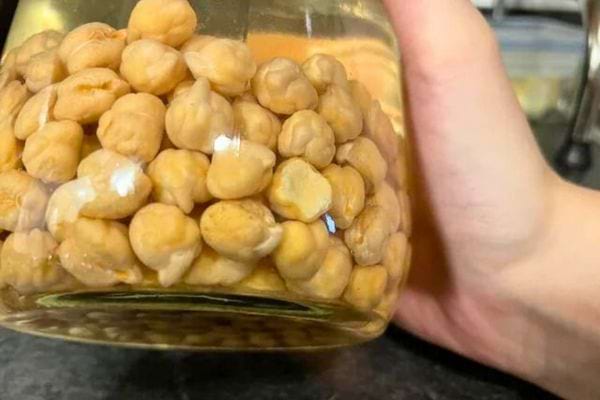 Un bocal contenant des pois chiches trempés dans l'eau, montrant les peaux qui se détachent.