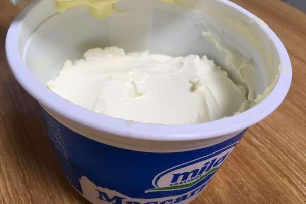 Un pot ouvert de mascarpone montrant la texture crémeuse du fromage.