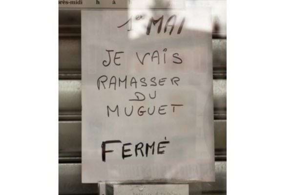 Vitrine avec un panneau indiquant : "1er mai, fermé pour ramasser du muguet." Annonce humoristique.