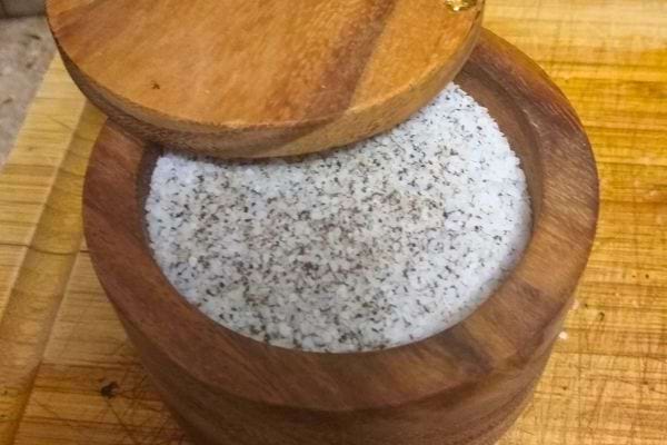 Sel mélangé à des particules noires dans un pot en bois.
