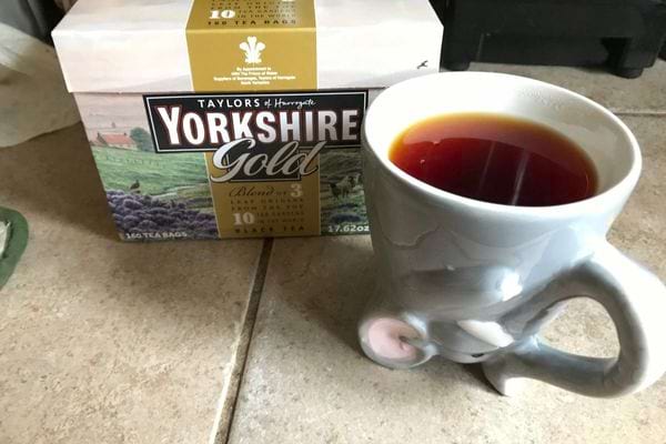 Une tasse de thé infusé à côté d'un paquet de thé "Yorkshire Gold,"