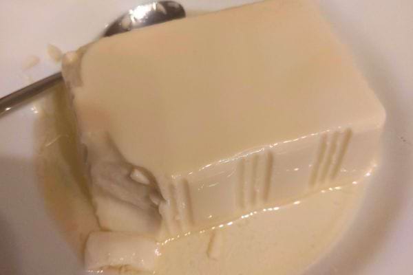 Bloc de tofu soyeux sur une assiette avec liquide.
