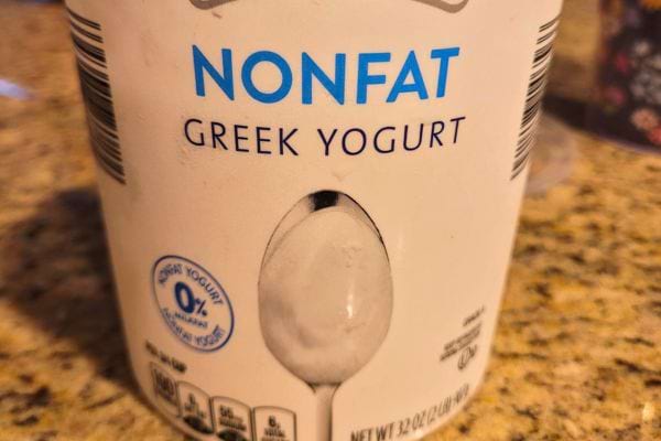 Un gros pot de yaourt grec non gras avec une cuillère sur l'étiquette.