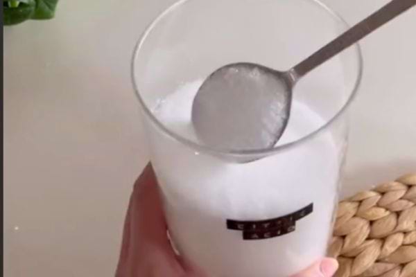 Main tenant un verre contenant du bicarbonate de soude.