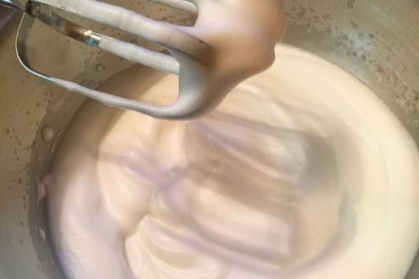 Fouettage de l'aquafaba en mousse blanche dans un bol.