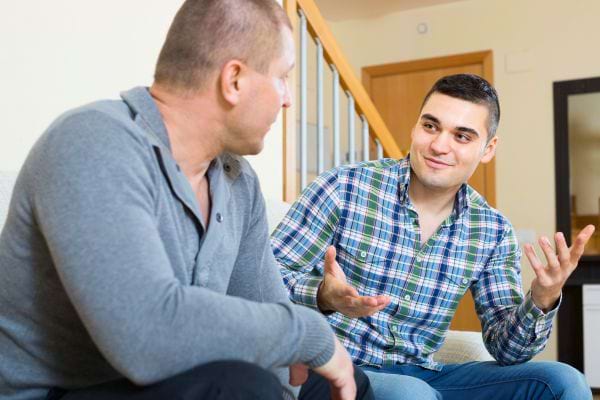 Deux hommes ont une discussion animée dans un cadre domestique.