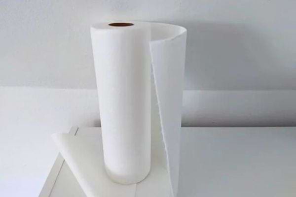 Un rouleau de papier essuie-tout blanc posé sur un plan de travail blanc.