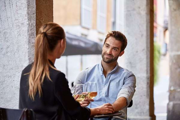 Un homme et une femme partageant un moment joyeux avec des bières à une table extérieure.