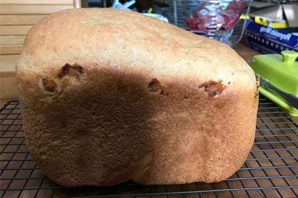 Pain de forme irrégulière, bien doré, posé sur une grille métallique.