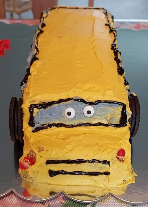 Gâteau en forme de bus jaune, détails caricaturaux et finition simpliste.