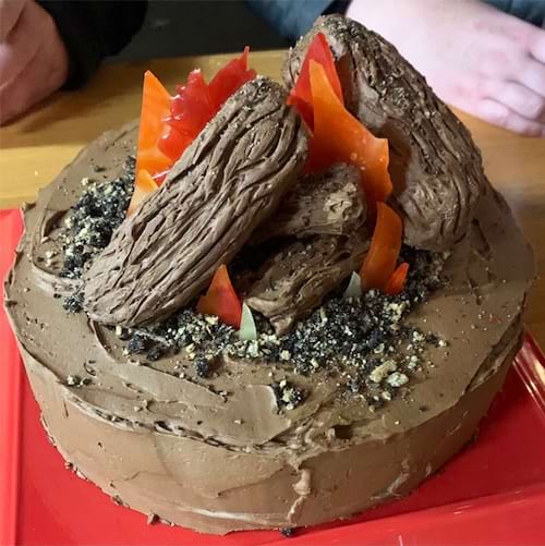 Gâteau rond imitant des excréments avec des bougies rouges.