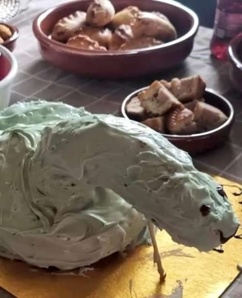 Gâteau en forme de dinosaure, aspect globuleux, détails faciaux comiques.