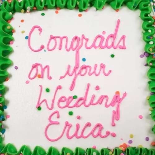 Un gâteau blanc orné d'un message de félicitations mal orthographié pour un mariage, en rose vif.
