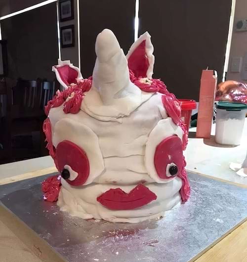 Gâteau licorne rose avec des yeux disproportionnés et une expression bizarre.