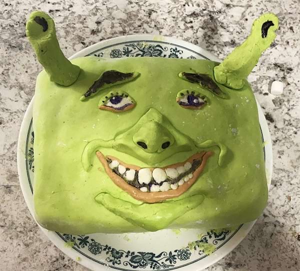 Gâteau de Shrek avec un large sourire édenté et des cornes mal placées.